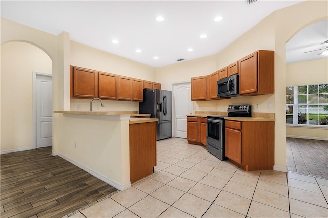 kitchen featuring kitchen peninsula, ceiling fan, sink, and stainless steel appliances