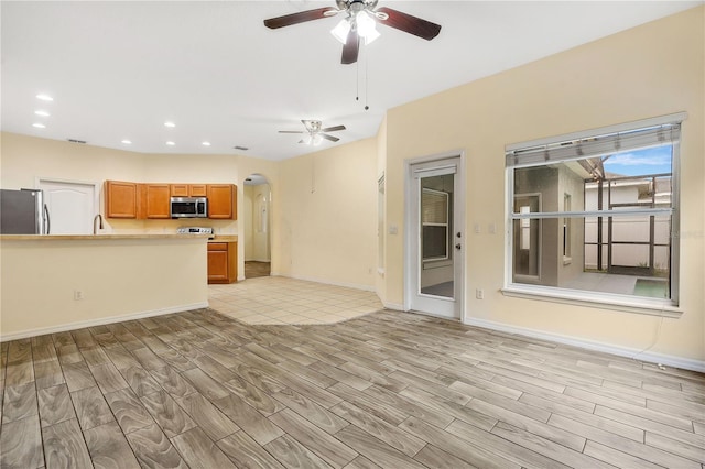 unfurnished living room featuring ceiling fan and sink