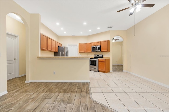 kitchen featuring kitchen peninsula, light wood-type flooring, stainless steel appliances, and ceiling fan