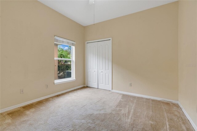 unfurnished bedroom with ceiling fan, light carpet, and a closet