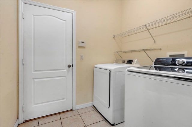 laundry area with washing machine and dryer and light tile patterned floors