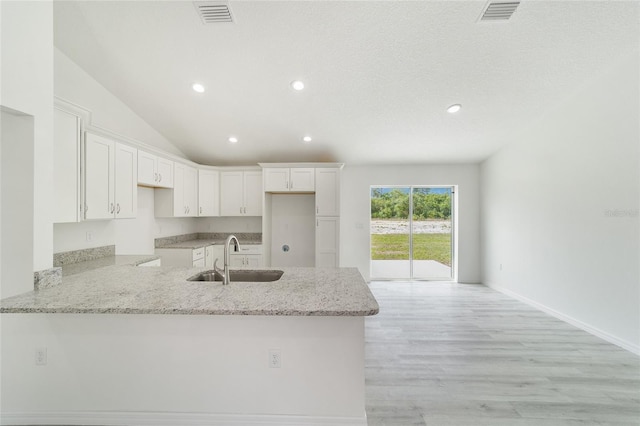 kitchen featuring white cabinets, sink, light stone countertops, light hardwood / wood-style floors, and kitchen peninsula