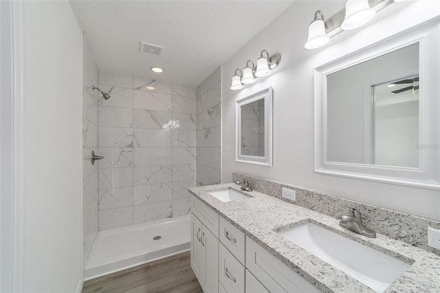 bathroom featuring hardwood / wood-style flooring, vanity, and a tile shower