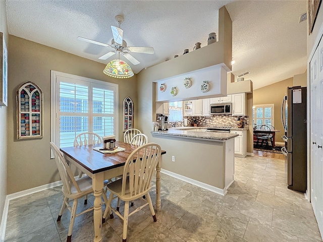 dining area with a textured ceiling, vaulted ceiling, ceiling fan, and sink