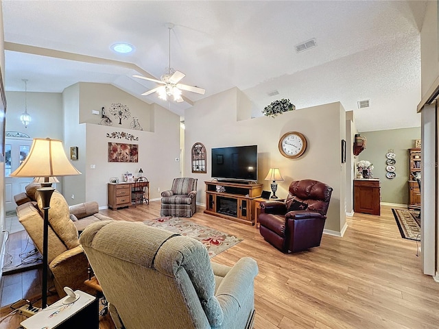 living room with a textured ceiling, light hardwood / wood-style floors, high vaulted ceiling, and ceiling fan