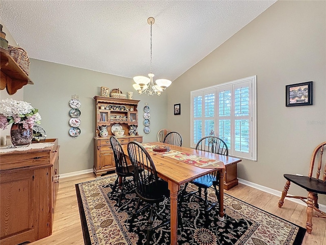 dining area featuring an inviting chandelier, lofted ceiling, a textured ceiling, and light hardwood / wood-style flooring