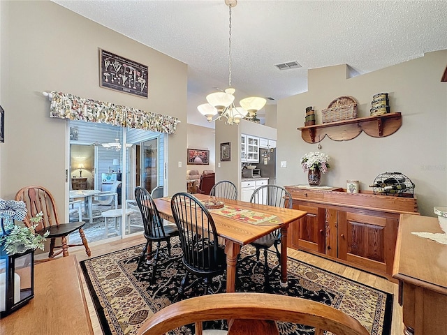 dining area with hardwood / wood-style floors, a textured ceiling, and a notable chandelier