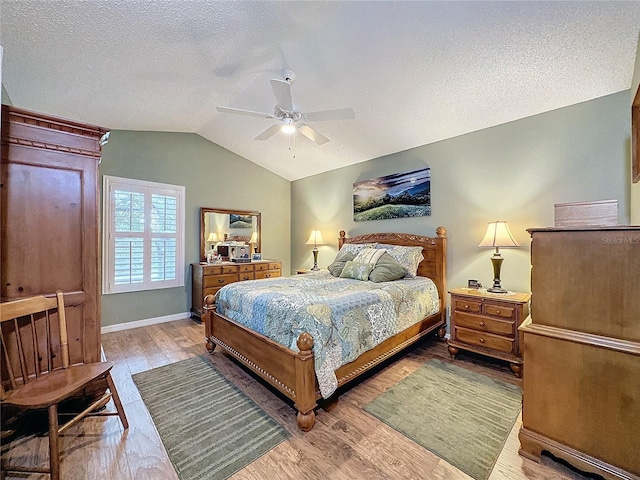 bedroom featuring a textured ceiling, hardwood / wood-style flooring, ceiling fan, and lofted ceiling