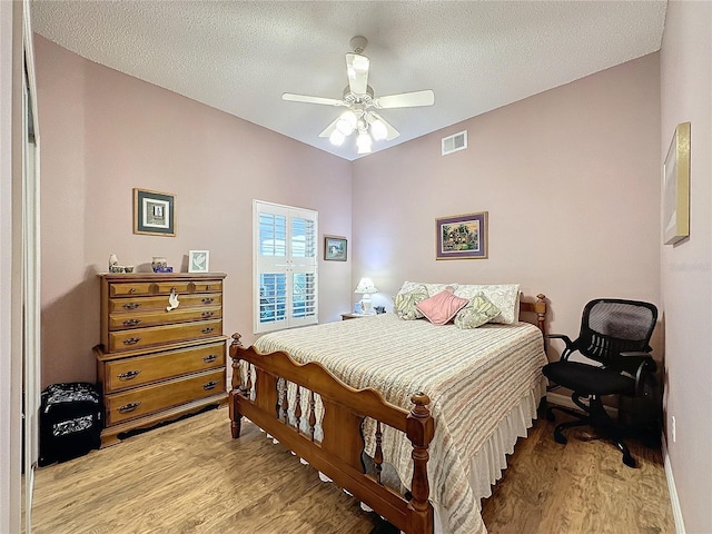 bedroom with ceiling fan, light hardwood / wood-style flooring, and a textured ceiling