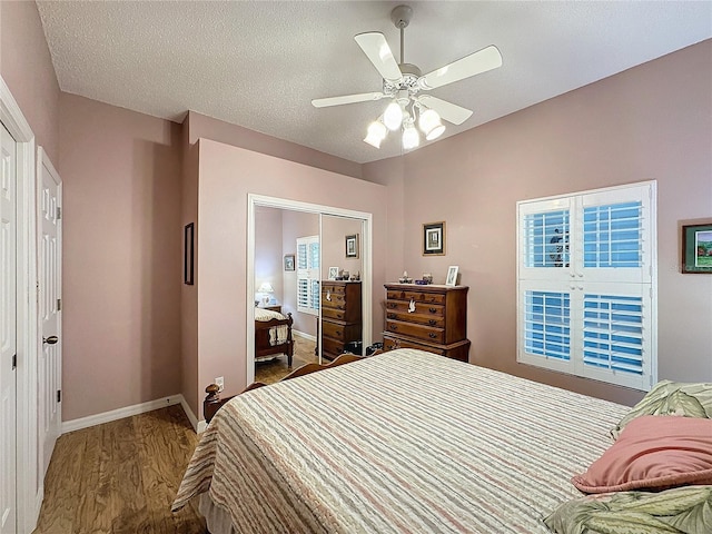 bedroom featuring ceiling fan, wood-type flooring, a textured ceiling, and a closet