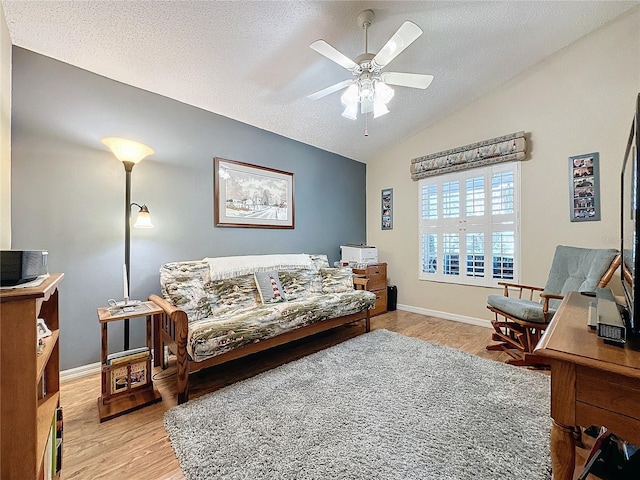 living room with a textured ceiling, ceiling fan, vaulted ceiling, and light wood-type flooring