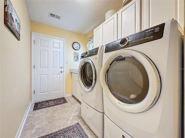 washroom featuring cabinets, independent washer and dryer, and a textured ceiling