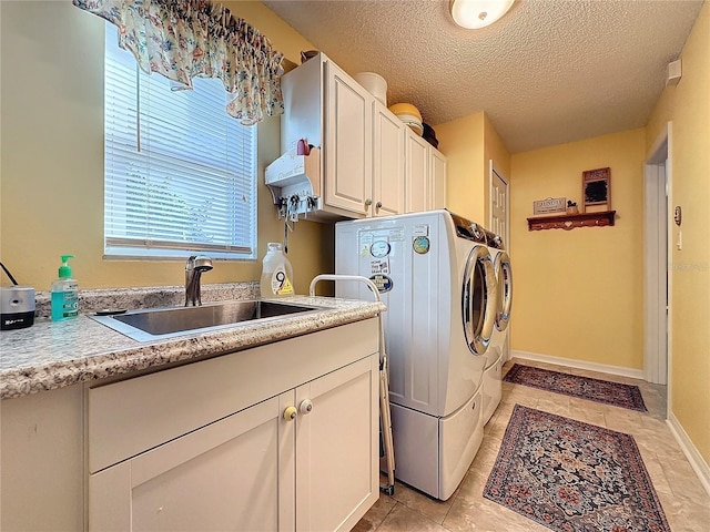 washroom featuring washer and clothes dryer, cabinets, sink, and a textured ceiling