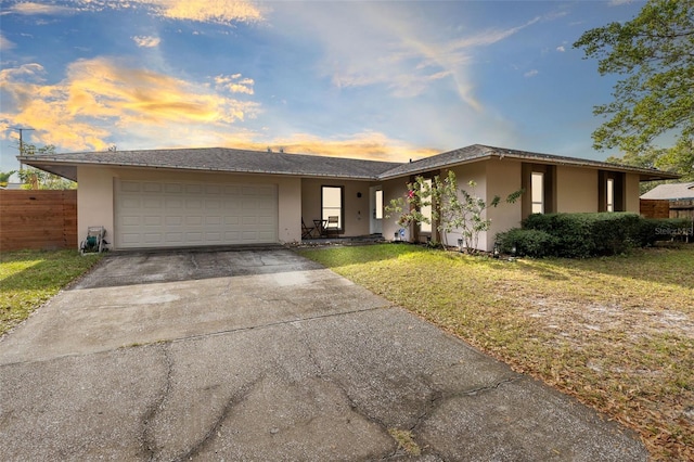 ranch-style home with a garage and a yard