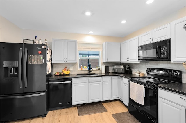 kitchen with white cabinetry, sink, decorative backsplash, black appliances, and light wood-type flooring