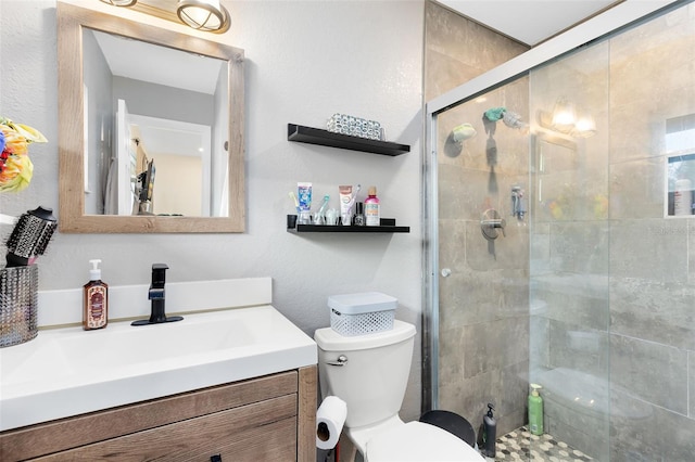 bathroom with vanity, a shower with shower door, and toilet