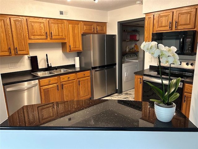 kitchen with a textured ceiling, washing machine and dryer, stainless steel appliances, and sink