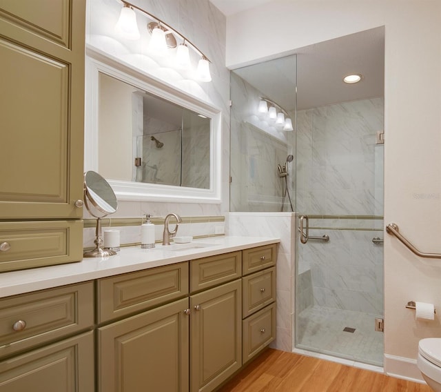 bathroom with hardwood / wood-style flooring, vanity, toilet, and a shower with shower door