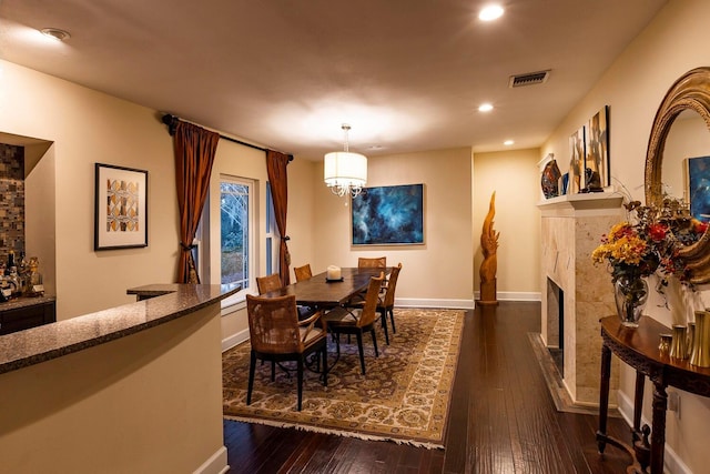 dining area with a fireplace, dark wood-type flooring, and a notable chandelier