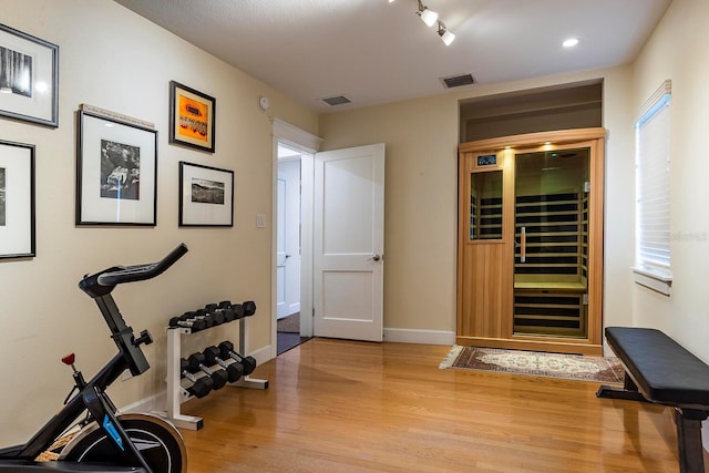 workout room featuring beverage cooler and light wood-type flooring