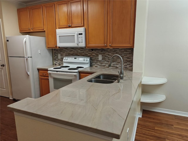 kitchen with kitchen peninsula, white appliances, tasteful backsplash, and sink