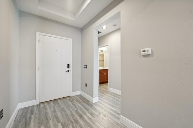 foyer entrance with light wood-type flooring and a tray ceiling