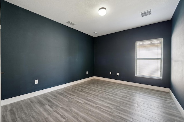 empty room with light hardwood / wood-style floors and a textured ceiling