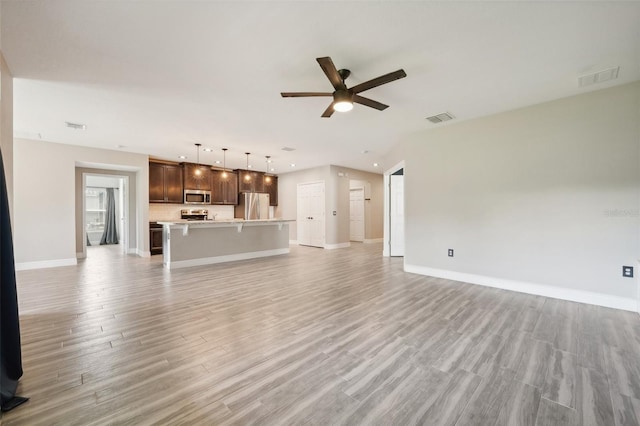 unfurnished living room featuring ceiling fan and light hardwood / wood-style floors