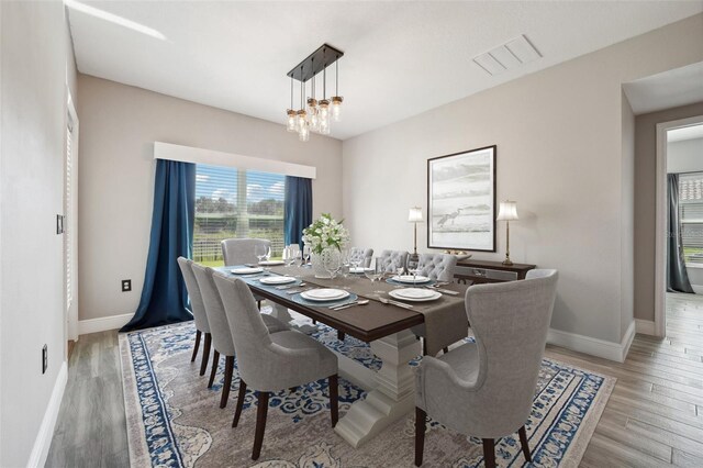 dining room with light hardwood / wood-style floors and a notable chandelier