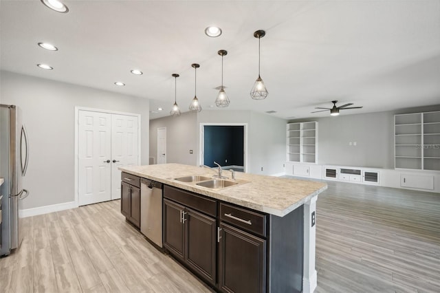 kitchen with ceiling fan, sink, stainless steel appliances, an island with sink, and decorative light fixtures