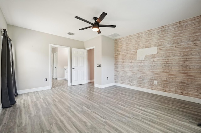 unfurnished bedroom with ceiling fan, light hardwood / wood-style flooring, and wood walls