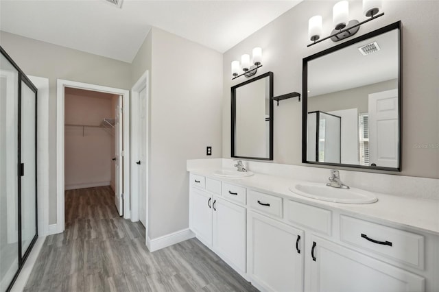 bathroom with hardwood / wood-style floors, vanity, and a shower with shower door