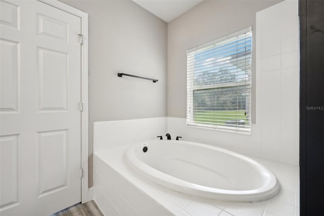 bathroom with hardwood / wood-style floors and tiled tub