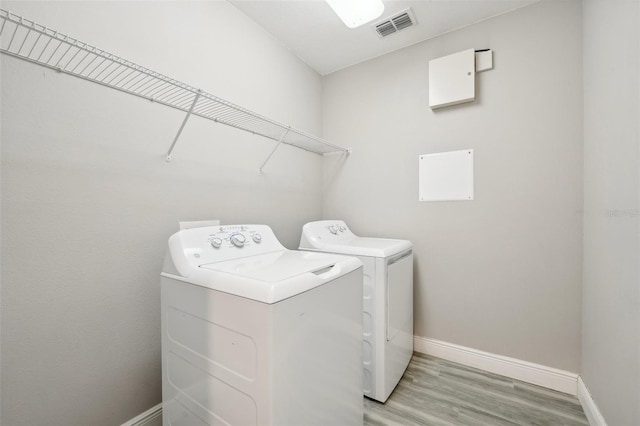 laundry area with separate washer and dryer and light hardwood / wood-style flooring