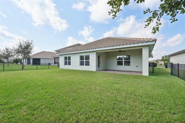 back of property with ceiling fan and a yard