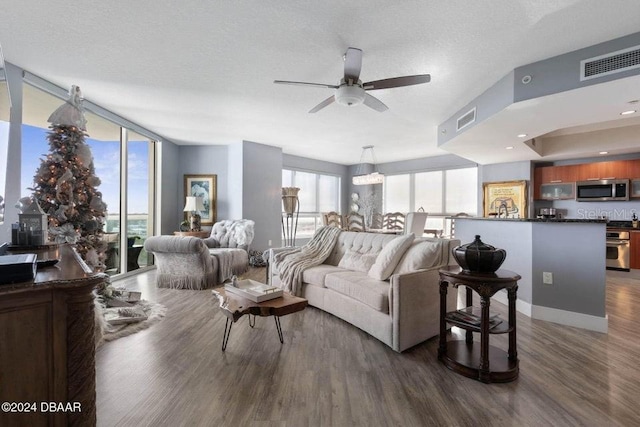 living room with a textured ceiling, ceiling fan with notable chandelier, and dark hardwood / wood-style floors