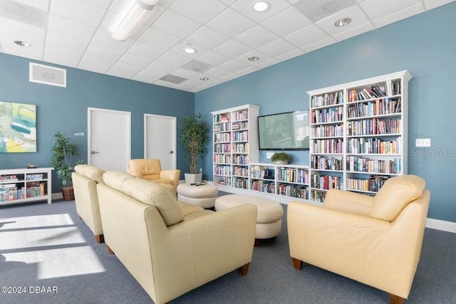 living area featuring carpet flooring and a drop ceiling