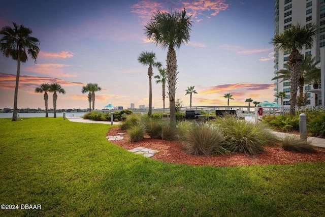 yard at dusk featuring a water view