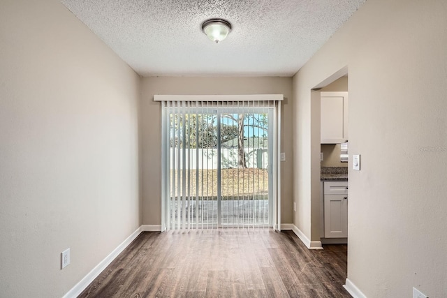 interior space with a textured ceiling and dark hardwood / wood-style flooring