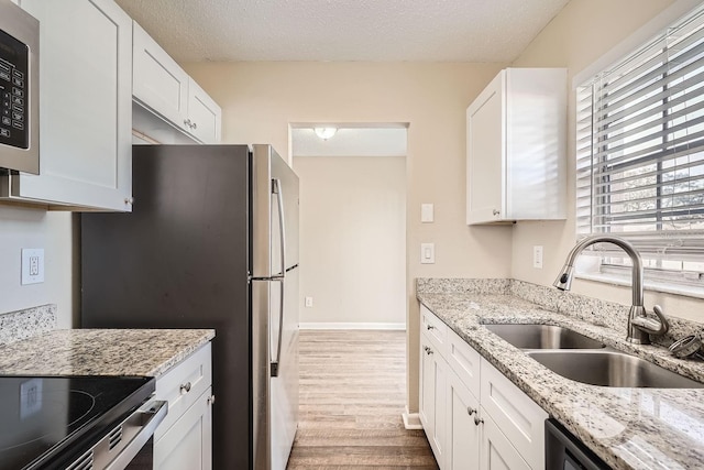 kitchen with light stone counters, white cabinets, and sink