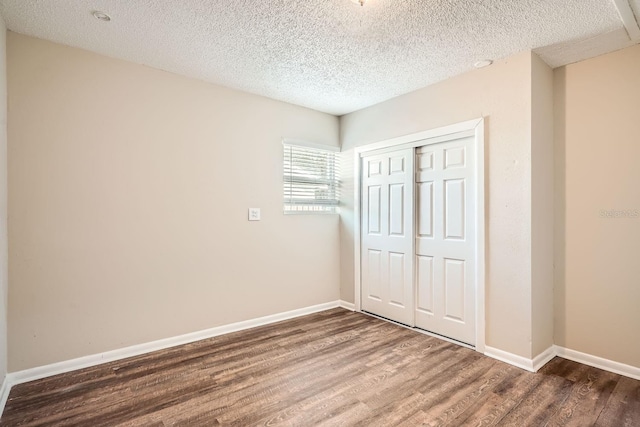 unfurnished bedroom with a textured ceiling, a closet, and wood-type flooring