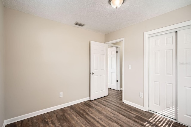 unfurnished bedroom with a textured ceiling, a closet, and dark hardwood / wood-style flooring