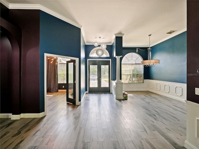 foyer entrance featuring crown molding, hardwood / wood-style floors, an inviting chandelier, and french doors