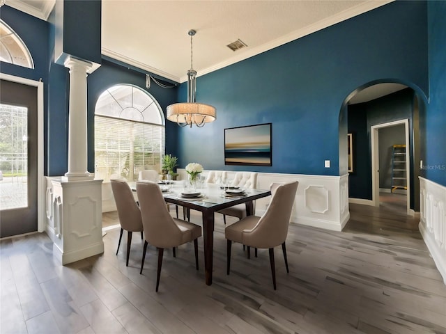 dining space with hardwood / wood-style floors, crown molding, and ornate columns