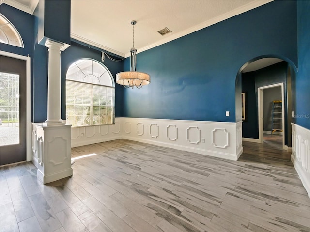 unfurnished dining area featuring ornamental molding, light hardwood / wood-style floors, and ornate columns