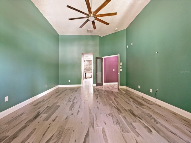 unfurnished room featuring a textured ceiling, light hardwood / wood-style flooring, ceiling fan, and vaulted ceiling