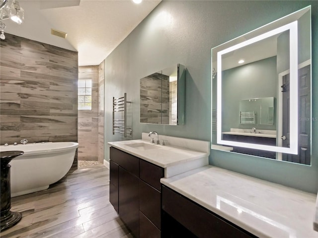 bathroom with radiator heating unit, wood-type flooring, a washtub, and vanity