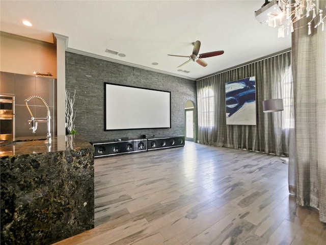 home theater room with hardwood / wood-style floors, crown molding, sink, and ceiling fan