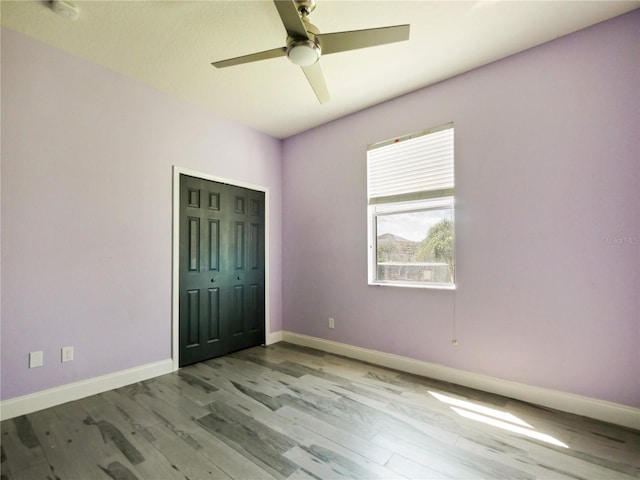 unfurnished bedroom with ceiling fan, light wood-type flooring, and a closet