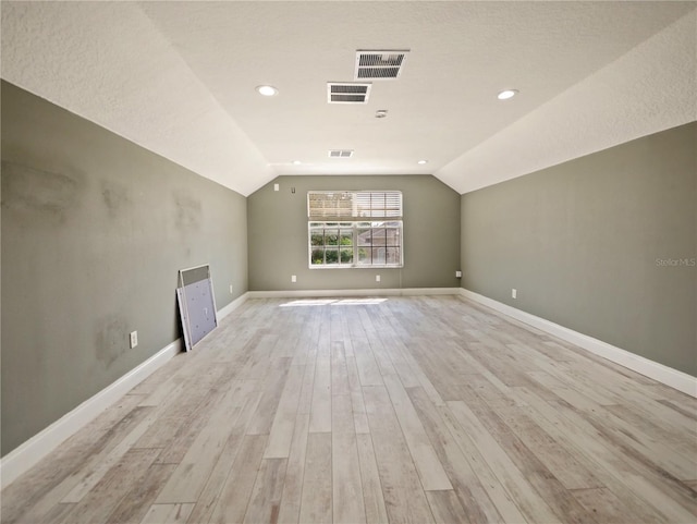 additional living space with light hardwood / wood-style floors and vaulted ceiling